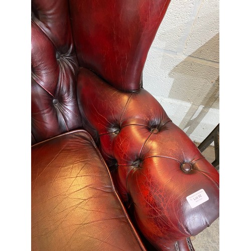 92 - Oxblood leather button back Chesterfield wing armchair (90W cm) & footstool