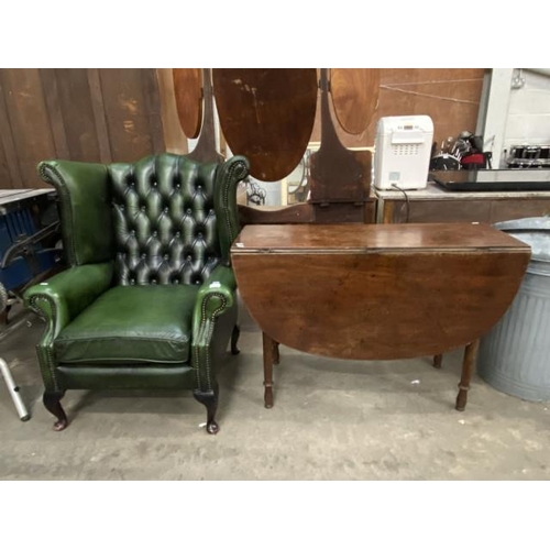 68 - Green leather button back Chesterfield wing armchair 90W and an oak drop leaf table 72H 107W 130D