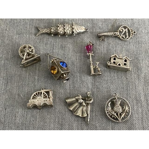 192 - 9 silver charms inc. lantern, house, articulated fish, mill, thistle, key etc.