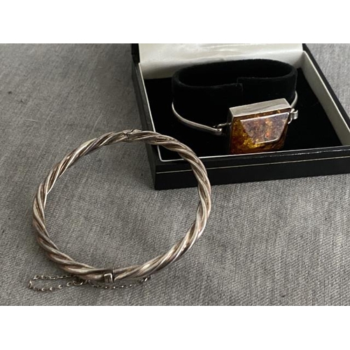 354 - 2 silver bangles, one set with faux amber