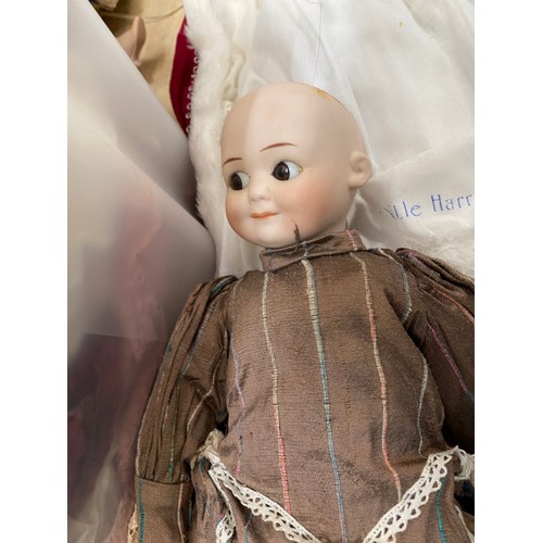 557 - A collection of clothed bisque headed dolls, assorted dolls clothing etc