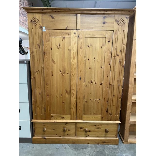 132 - Waxed pine two door wardrobe with two drawers to the underneath (hanging rail to the interior) and o... 