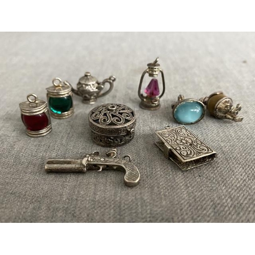 376 - 9 silver tone charms inc. miners lamp, Holy Bible, teapot, flintlock pistol, policeman etc.