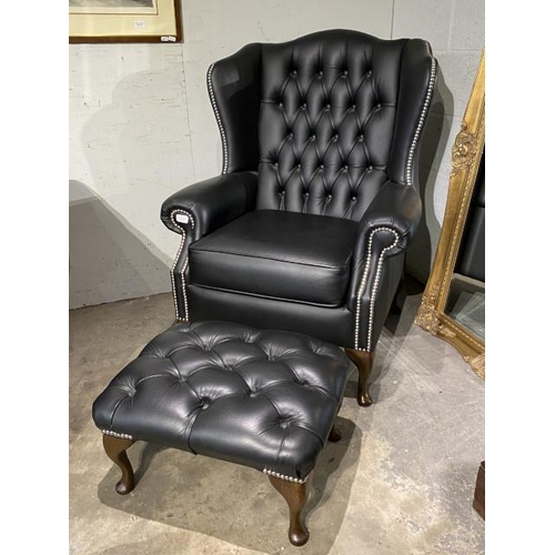 145 - Hand made black leather button back Chesterfield wing armchair 108H 80W 73D and a matching footstool... 