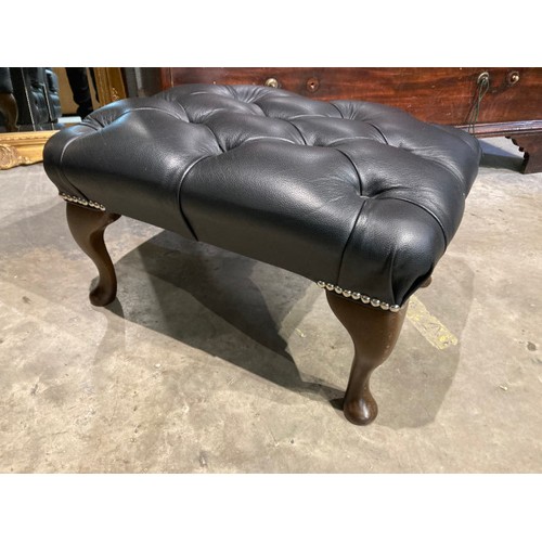 145 - Hand made black leather button back Chesterfield wing armchair 108H 80W 73D and a matching footstool... 