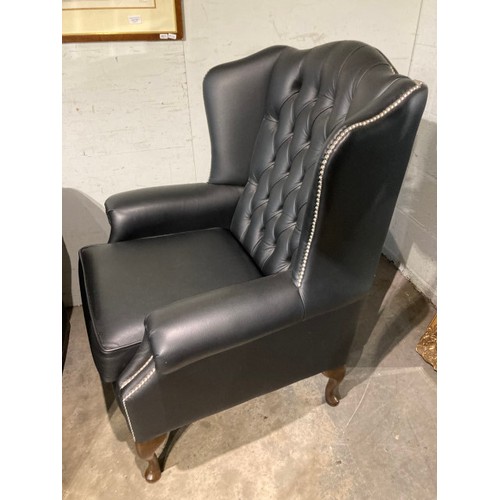 145 - Hand made black leather button back Chesterfield wing armchair 108H 80W 73D and a matching footstool... 