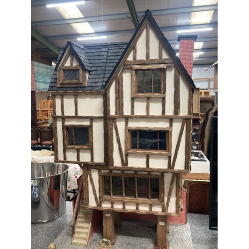 198 - Handmade Tudor style three-storey doll's house raised on four pillars with stairs to the side-door &... 