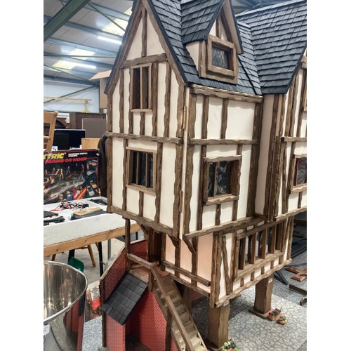 198 - Handmade Tudor style three-storey doll's house raised on four pillars with stairs to the side-door &... 