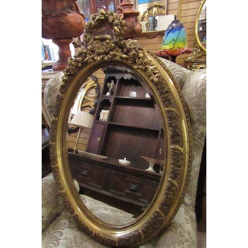 147 - Oval Form Gilded Wall Mirror with Upper Cartouche Decoration Approximately 32 Inches High