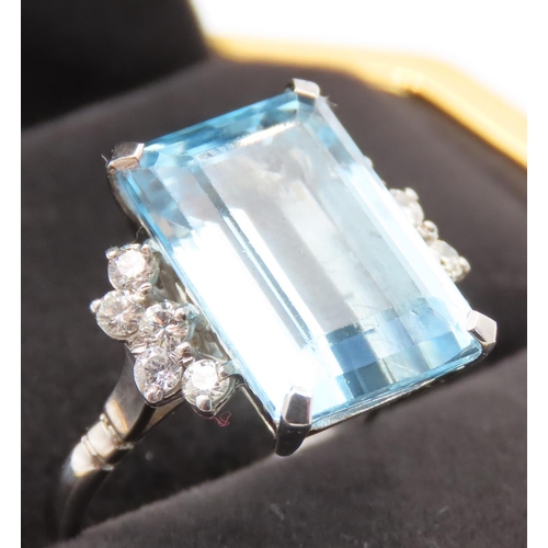 Emerald Cut 11ct Aquamarine Statement Ring with Further Diamond Decoration to Shoulders Mounted in 18 Carat White Gold Total Diamond Carat Weight Approximately 0.6ct Ring Size P