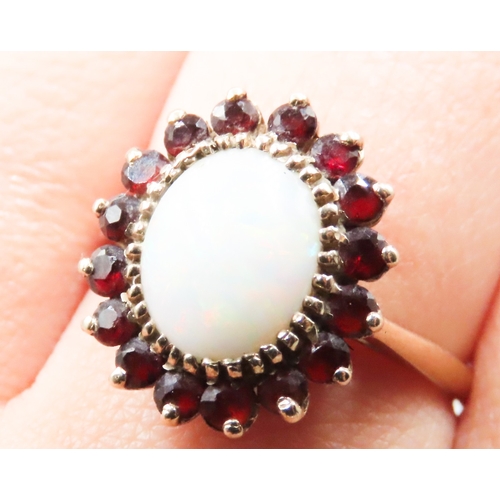 228 - Opal Set Centre Stone with Red Garnet Set Halo Surround Mounted in 9 Carat Yellow Gold Ring Size R