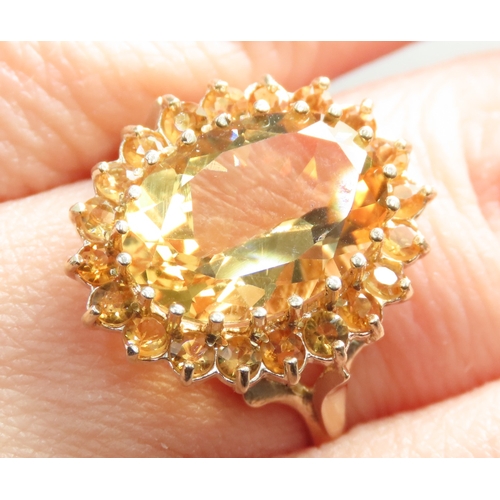 155 - Oval Cut Citrine Set Ring with Further Citrine Set Halo Mounted in 9 Carat Yellow Gold Ring Size O