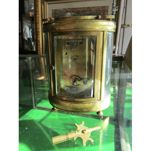 1122 - Oval Form Brass Bound Carriage Clock with Key Attractively Detailed Approximately 5 Inches High