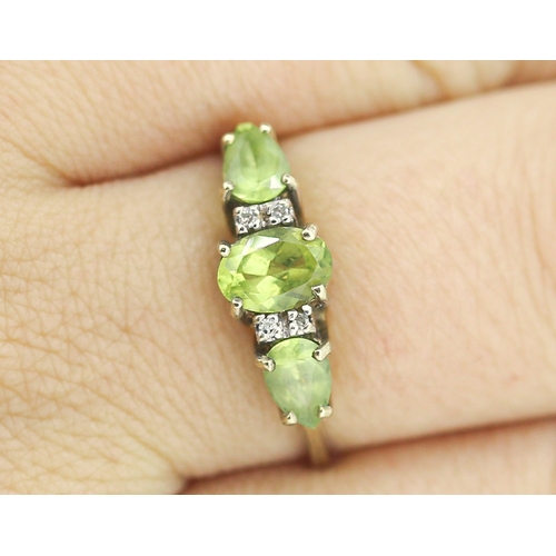 49 - Peridot Set Three Stone Ring with Further Diamond Insets Mounted in 9 Carat Yellow Gold Ring Size T