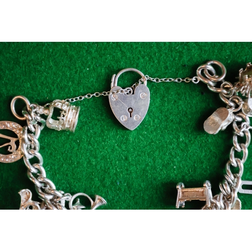 47 - Silver Charm Bracelet Adorned with Various Charms Safety Chain and Padlock Motif Clasp Present