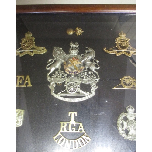 70 - Collection in large wood and glass frame of metal cap badges, shoulder titles etc, including QV 1st ... 