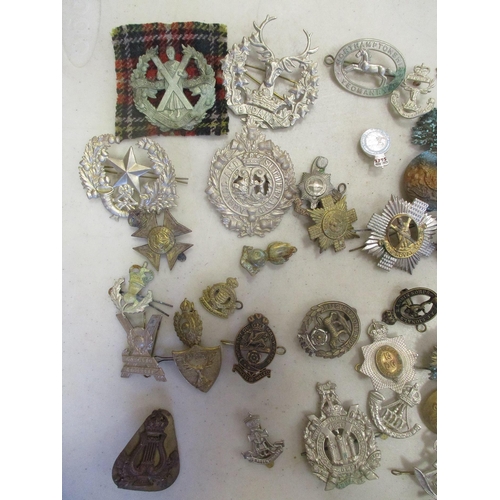 130 - Accumulation of metal cap badges, collar dogs, pin badges etc with range of regiments including 19th... 