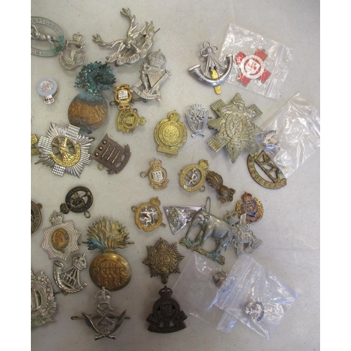 130 - Accumulation of metal cap badges, collar dogs, pin badges etc with range of regiments including 19th... 