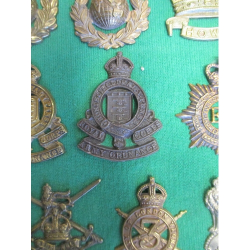 102 - Collection of cap badges with odd arm badge etc mounted on foam board in large wooden frame (91cm x ... 