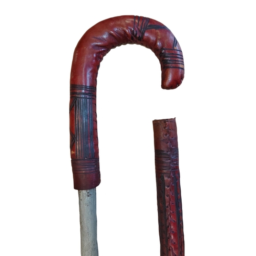 65 - Somali stick sword, dark red leather, crook style handle, pitting to blade, about good very fine. BU... 