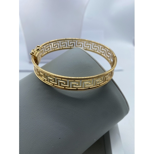 10 - A 9ct yellow gold Greek design ladies bangle, 14.5 grams in weight approx, fully hallmarked, safety ... 