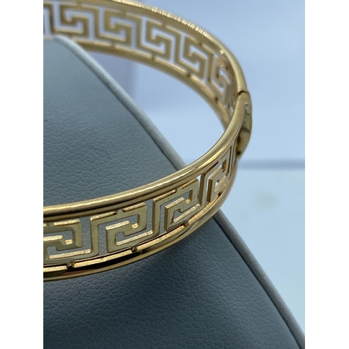 10 - A 9ct yellow gold Greek design ladies bangle, 14.5 grams in weight approx, fully hallmarked, safety ... 