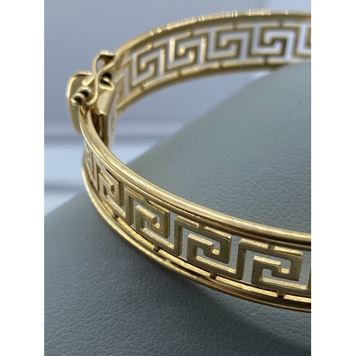 10 - A 9ct yellow gold Greek design ladies bangle, 14.5 grams in weight approx, fully hallmarked, safety ... 