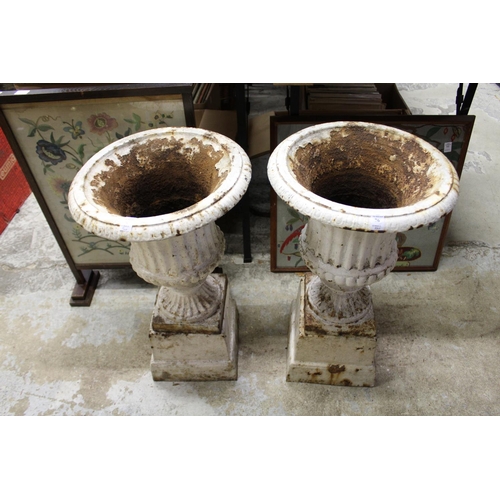 76 - A pair of painted cast iron garden urns on pedestal bases.