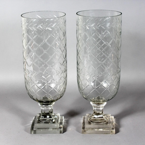 1058 - A PAIR OF SLICE CUT CIRCULAR GLASS STORM LAMPS on square stepped bases. 16ins high.