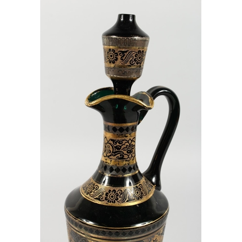 1062 - A CONTINENTAL DARK GREEN GLASS EWER AND STOPPER, with etched and gilded decoration. 14ins high.