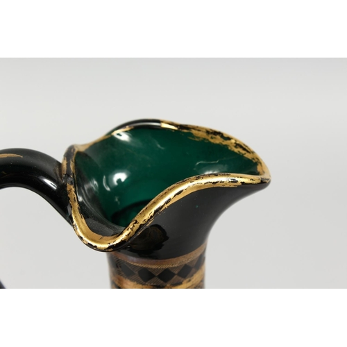 1062 - A CONTINENTAL DARK GREEN GLASS EWER AND STOPPER, with etched and gilded decoration. 14ins high.