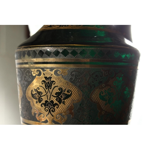 1062 - A CONTINENTAL DARK GREEN GLASS EWER AND STOPPER, with etched and gilded decoration. 14ins high.