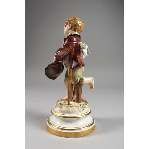 1118 - A MEISSEN PORCELAIN FIGURE OF A CHERUB holding a hat and walking with a stick. Cross swords mark in ... 