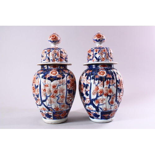 11 - A PAIR OF JAPANESE MEIJI PERIOD IMARI PORCELAIN VASES AND COVERS, with ribbed body's, and panels of ... 