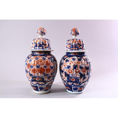 11 - A PAIR OF JAPANESE MEIJI PERIOD IMARI PORCELAIN VASES AND COVERS, with ribbed body's, and panels of ... 