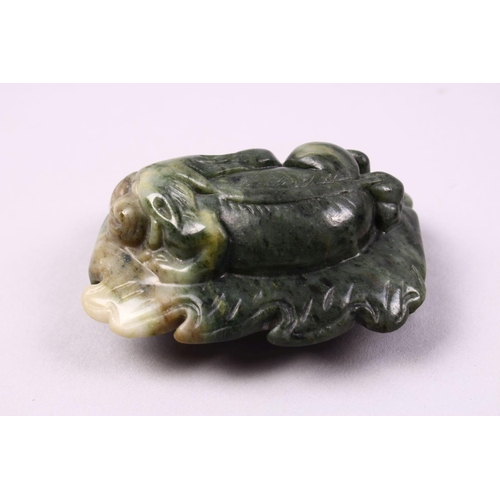 119 - A CHINESE CARVED JADE BELT BUCKLE / DECORATION OF A RECUMBENT KYLIN, upon a leaf, 6.5cm.