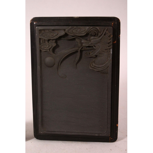 175 - A JAPANESE INK BLOCK, carved with a dragon in a lacquer box, 15cm wide.