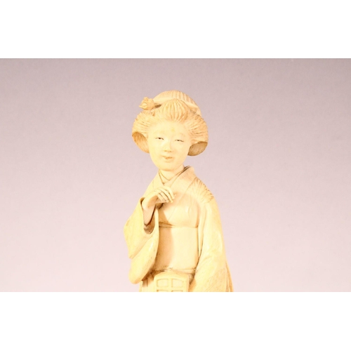 180 - AN EARLY 20TH CENTURY JAPANESE CARVED IVORY OKIMONO OF A GEISHA GIRL, mark to base, 20cm high.