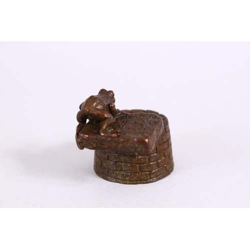 20 - A JAPANESE BRONZE FIGURE OF A TOAD OVER A WELL, with carved calligraphy to the toad base, the unders... 