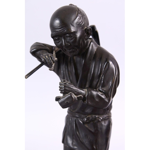 232 - A JAPANESE MEIJI PERIOD BRONZE OKIMONO - SMOKING MAN, the figure stood upon stylized base, holding h... 