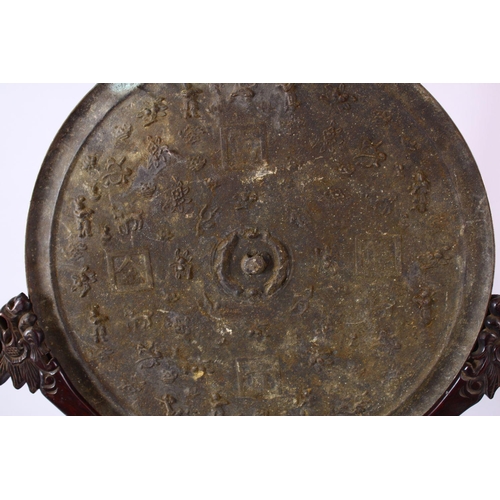 252 - A LARGE CHINESE CIRCULAR CAST BRONZE 'MIRROR' on a hardwood stand (stand AF), disc 46cm diameter.