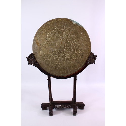 252 - A LARGE CHINESE CIRCULAR CAST BRONZE 'MIRROR' on a hardwood stand (stand AF), disc 46cm diameter.