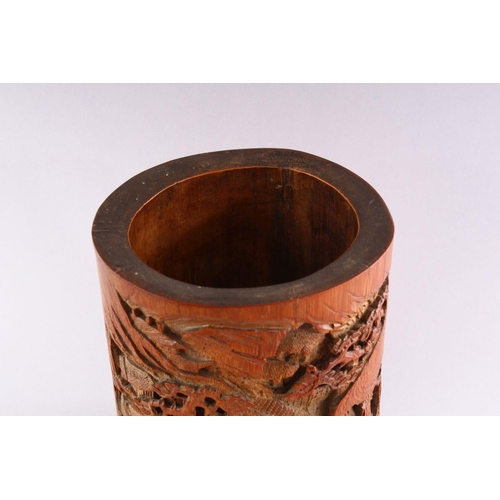 308 - A GOOD CHINESE BAMBOO BRUSH POT, deeply carved with figures in a mountainous landscape, 18cm high.