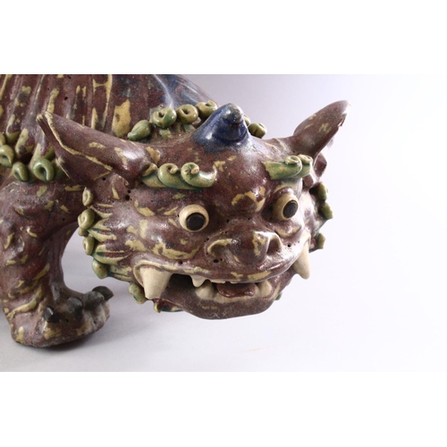 312 - A CHINESE MOULDED POTTERY LION DOG, 48cm long.