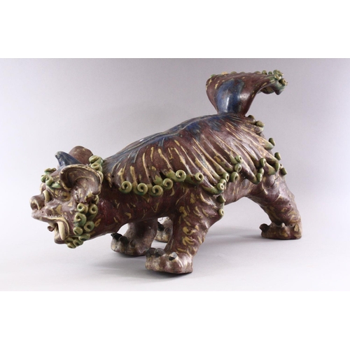 312 - A CHINESE MOULDED POTTERY LION DOG, 48cm long.