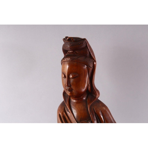 313 - A GOOD LARGE CHINESE CARVED WOOD FIGURE OF GUANYIN, standing on a dragon, 55cm high.