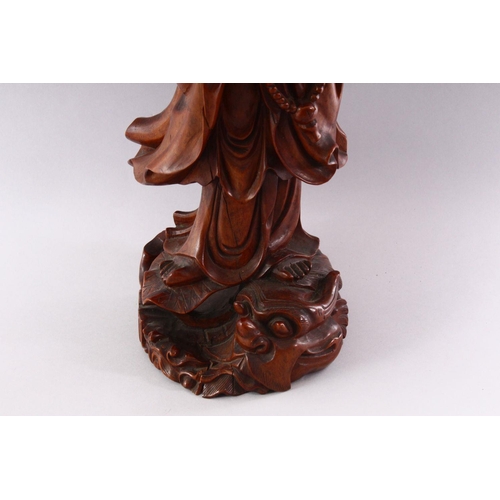 313 - A GOOD LARGE CHINESE CARVED WOOD FIGURE OF GUANYIN, standing on a dragon, 55cm high.