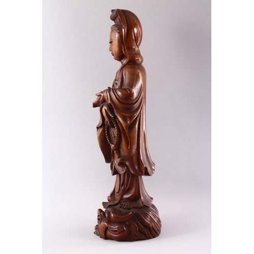 313 - A GOOD LARGE CHINESE CARVED WOOD FIGURE OF GUANYIN, standing on a dragon, 55cm high.