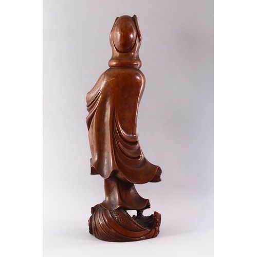 313 - A GOOD LARGE CHINESE CARVED WOOD FIGURE OF GUANYIN, standing on a dragon, 55cm high.