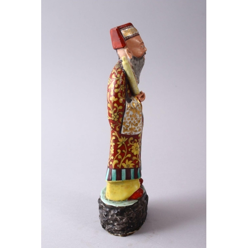 335 - A CHINESE FAMILLE ROSE POTTERY FIGURE OF A SCHOLAR, holding a scroll upon a stylized base, 22cm high... 